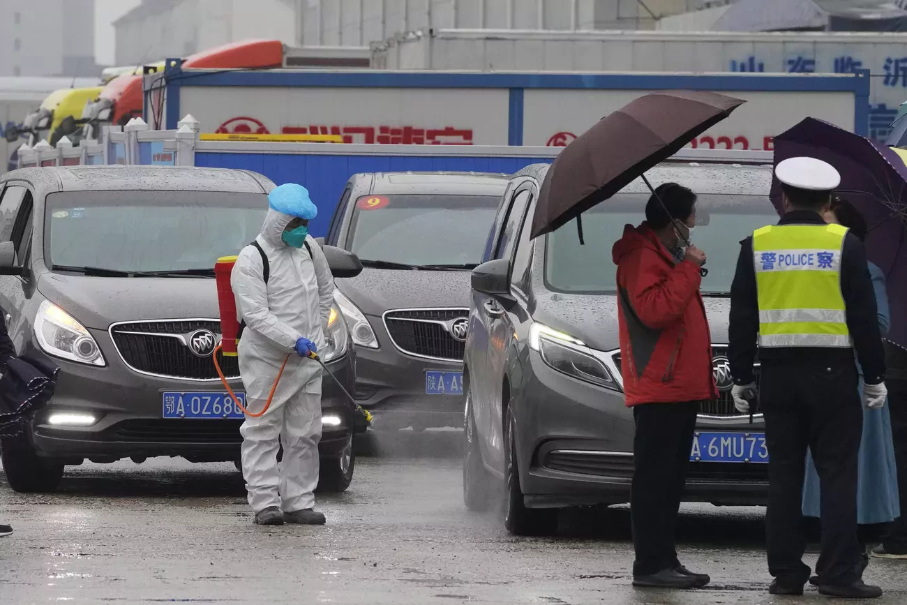 Un véhicule du convoi de l'Organisation mondiale de la santé est désinfecté lors de la visite par les experts du marché de gros de Baishazhou.