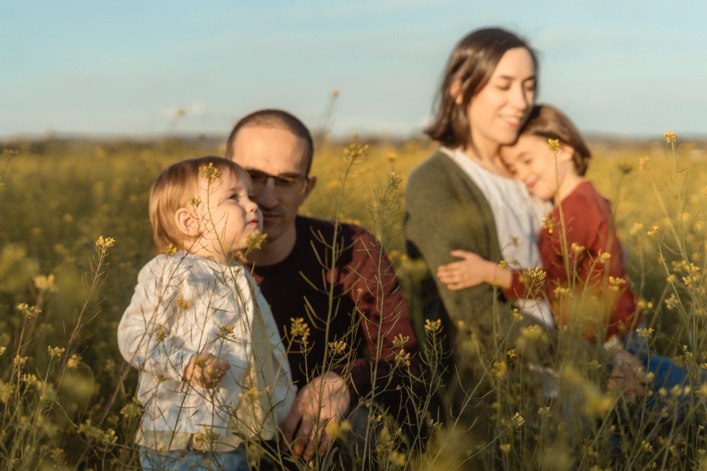 mamá, papá y dos niñas en un campo de flores