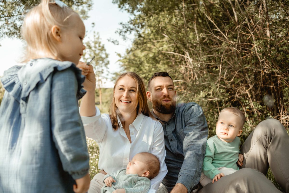 mamá y papá jugando con sus tres hijos con pompas de jabón