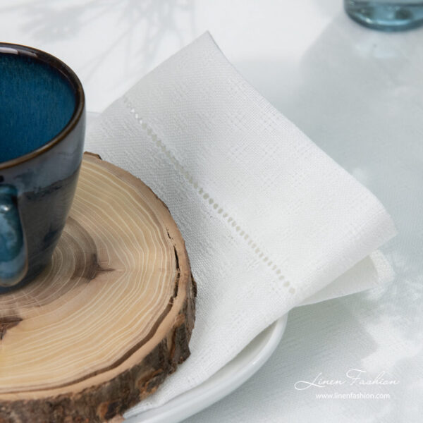 Border of white patterned linen napkin with hemstitch