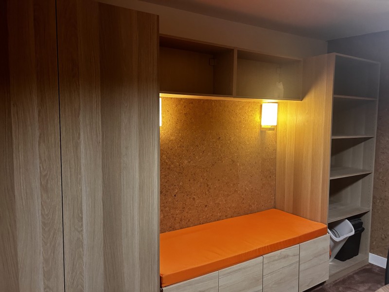 Niche éclairée avec banquette orange intégrée dans le studio podcast