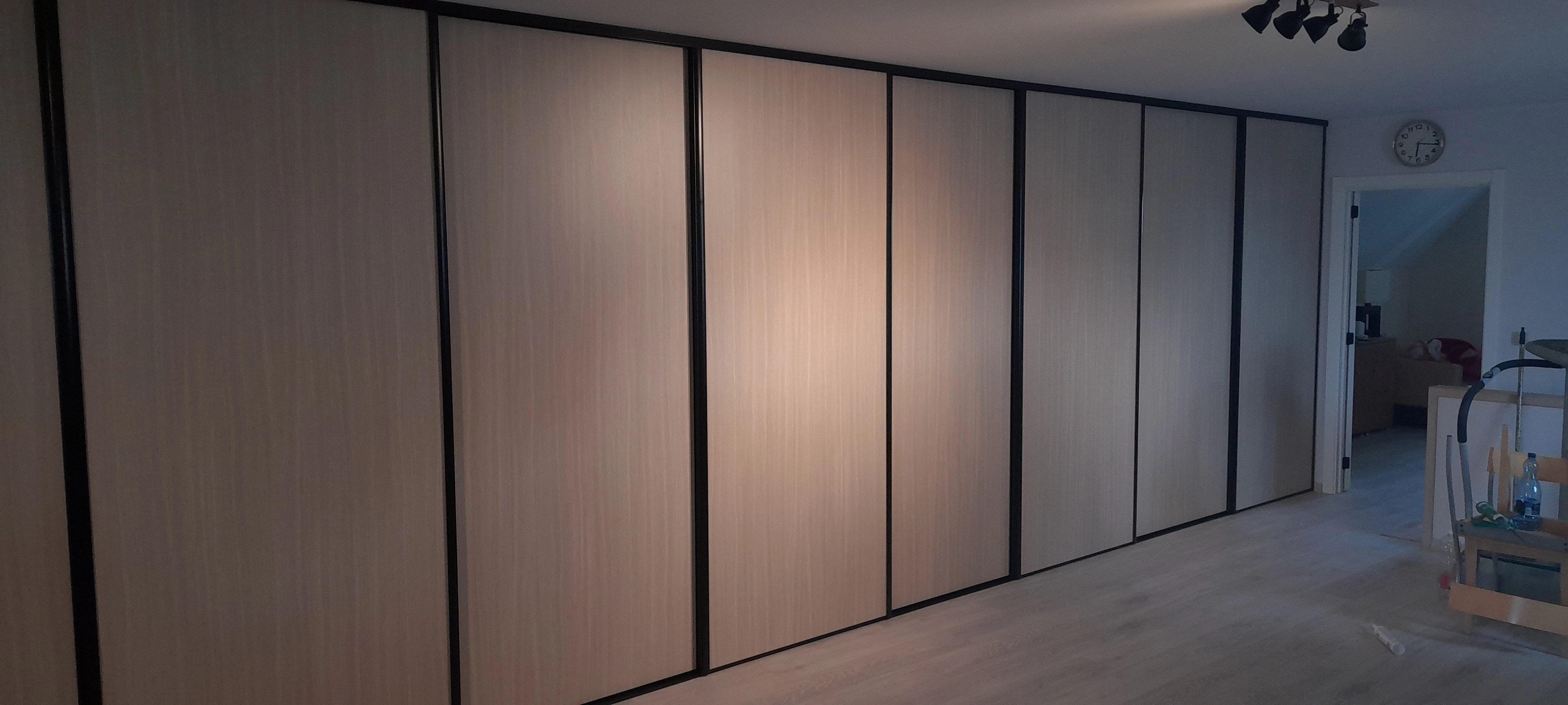 Wandbrede maatkast met lichte houtlook en zwarte profielen