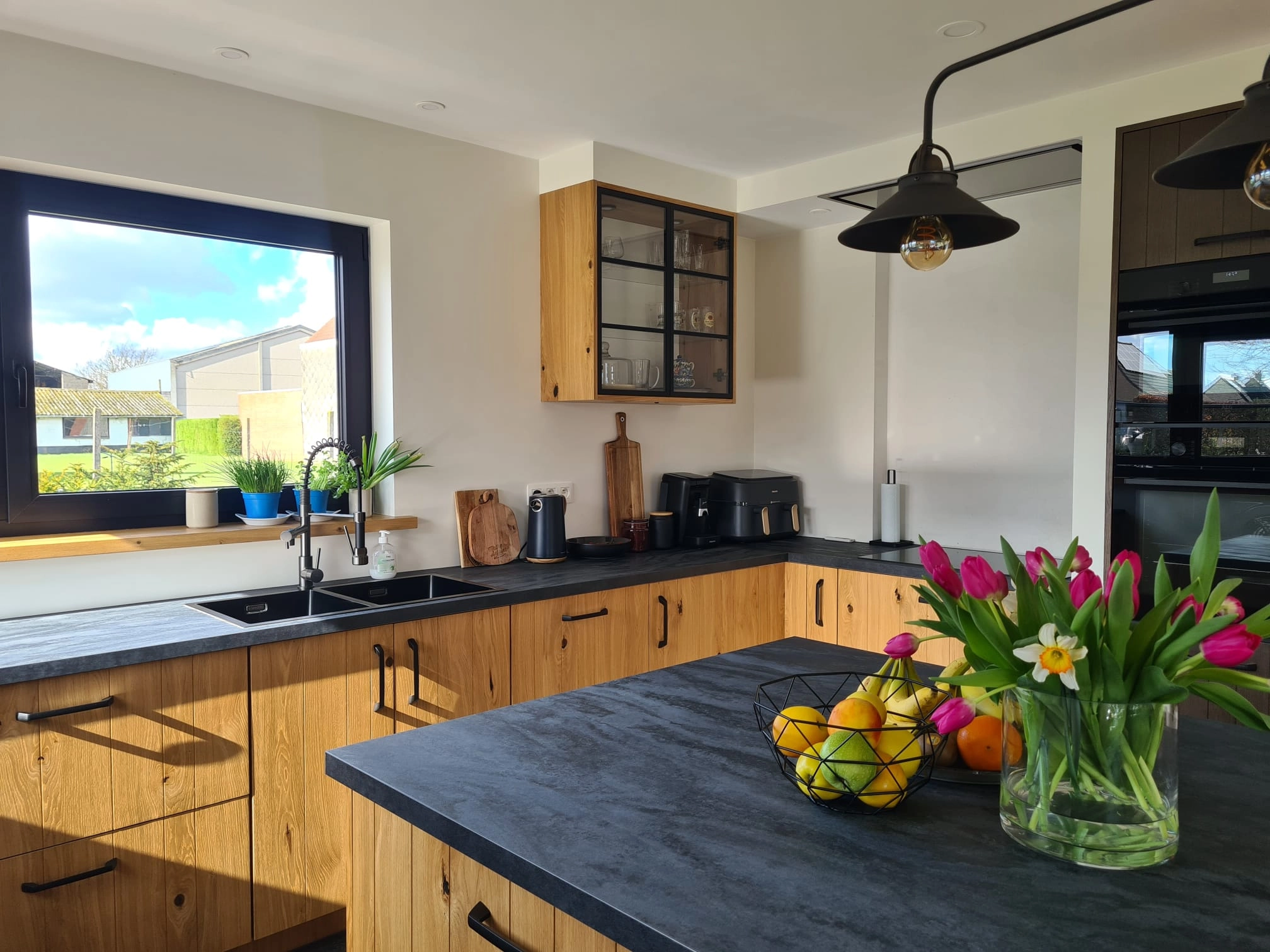Eiken keuken met donker werkblad en hoge kastenwand