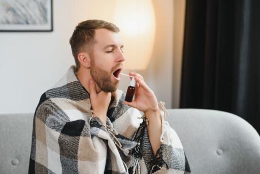 Uomo usa uno spray per curare la sua faringite