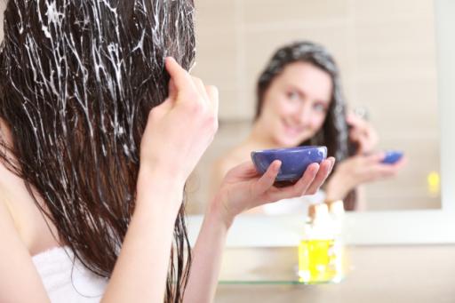 Una bellissima ragazza applica una maschera sui capelli per aumentarne la lucentezza