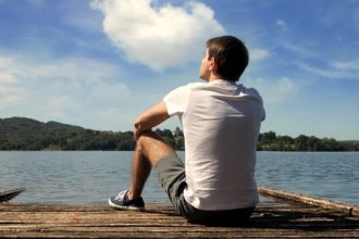 Bateau stop : jeune homme assis sur un quai