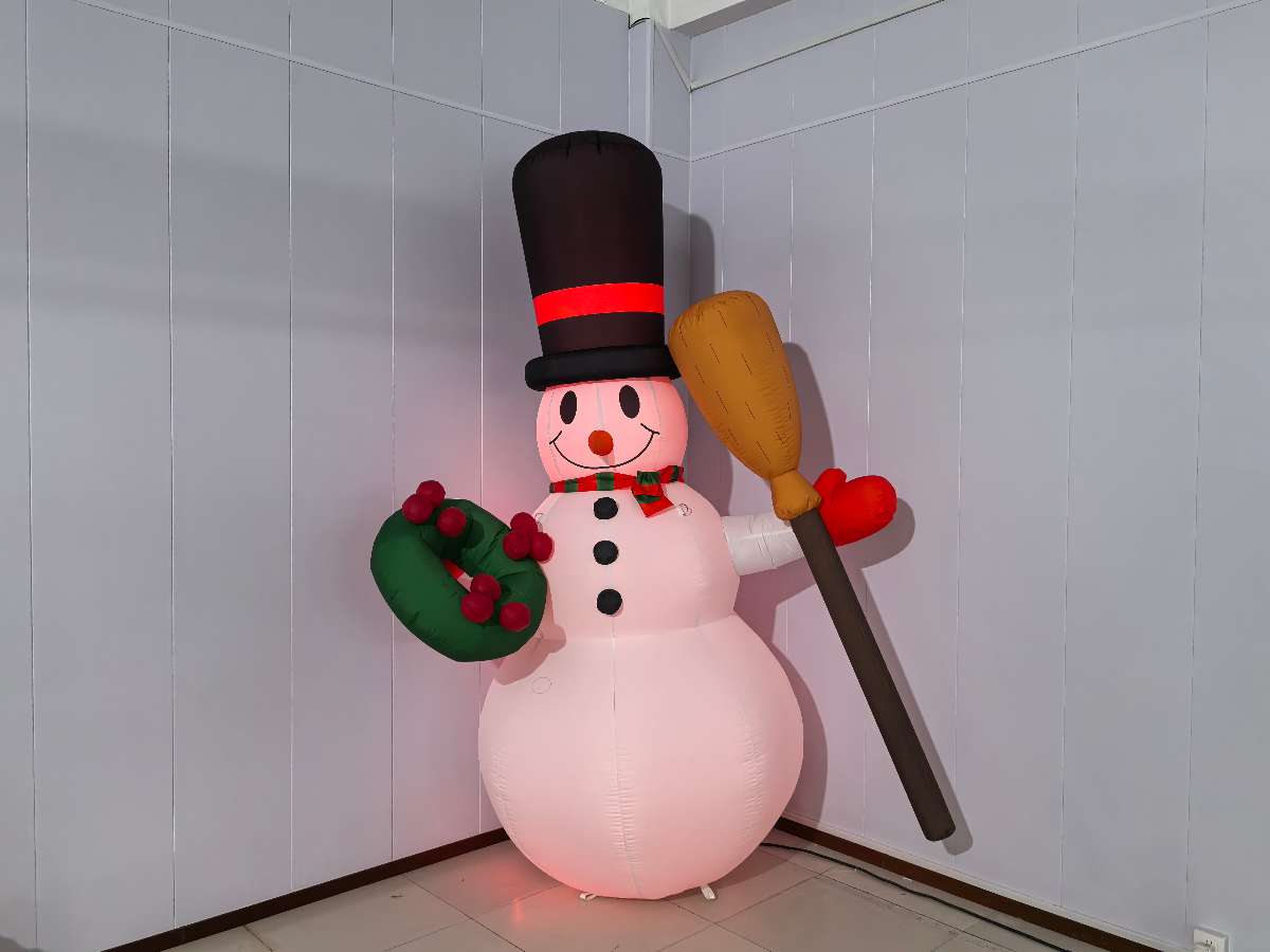 bonhomme de neige gonflable blanc éclairé en rouge  avec un ballon dans sa main gauche et un chapeau noir