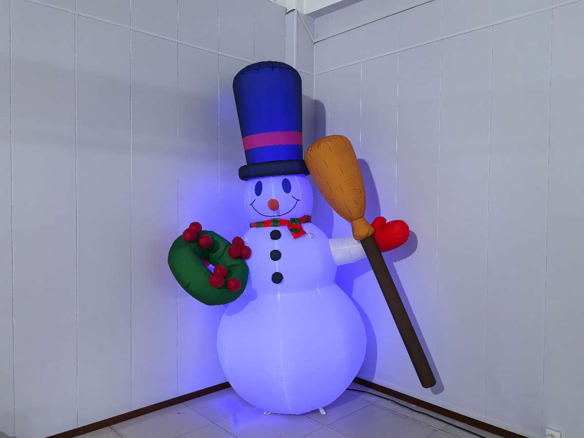 bonhomme de neige gonflable blanc éclairé en bleu  avec un ballon dans sa main gauche et un chapeau noir