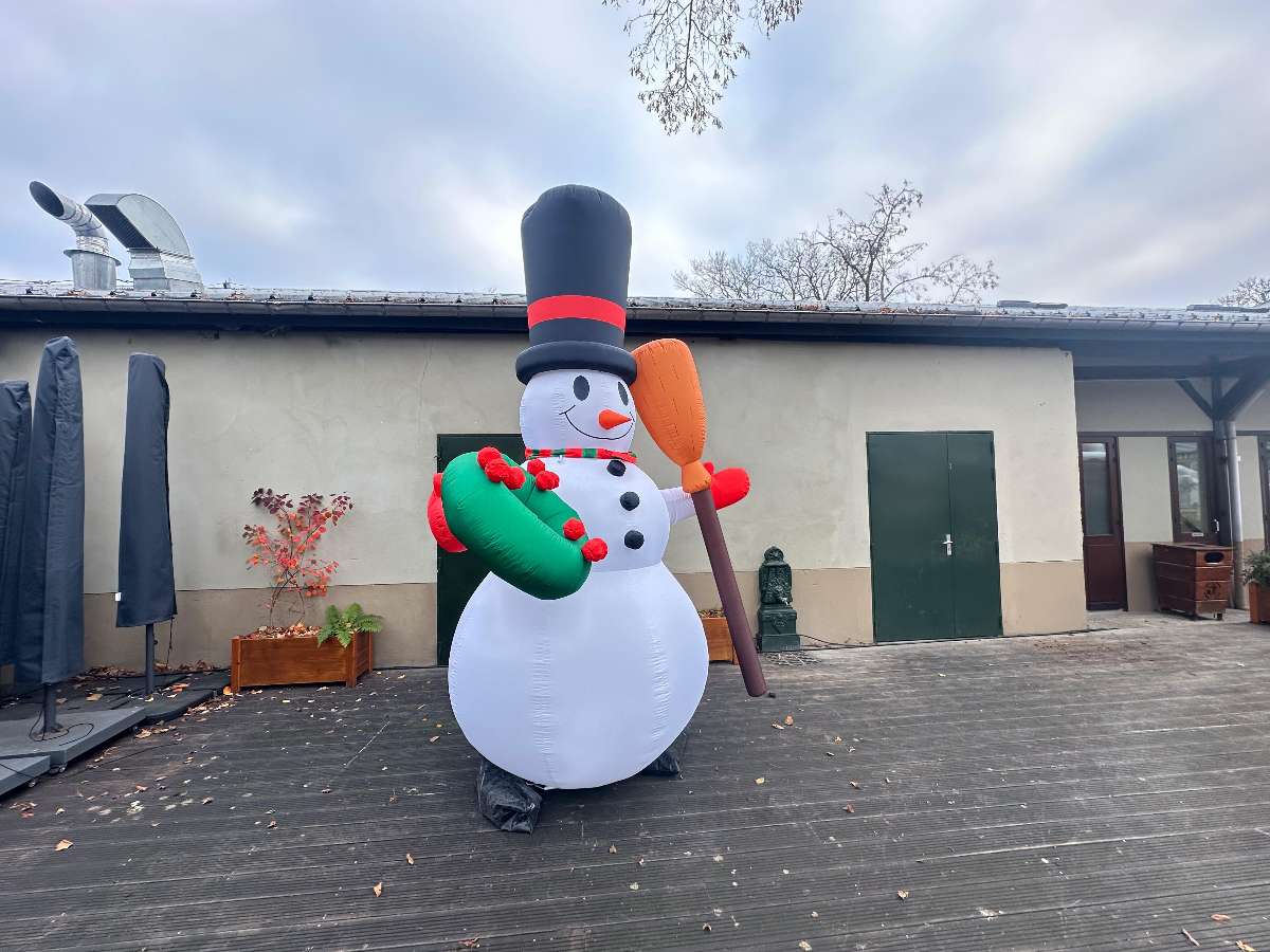bonhomme de neige gonflable blanc avec un balet dans sa main gauche et un chapeau noir