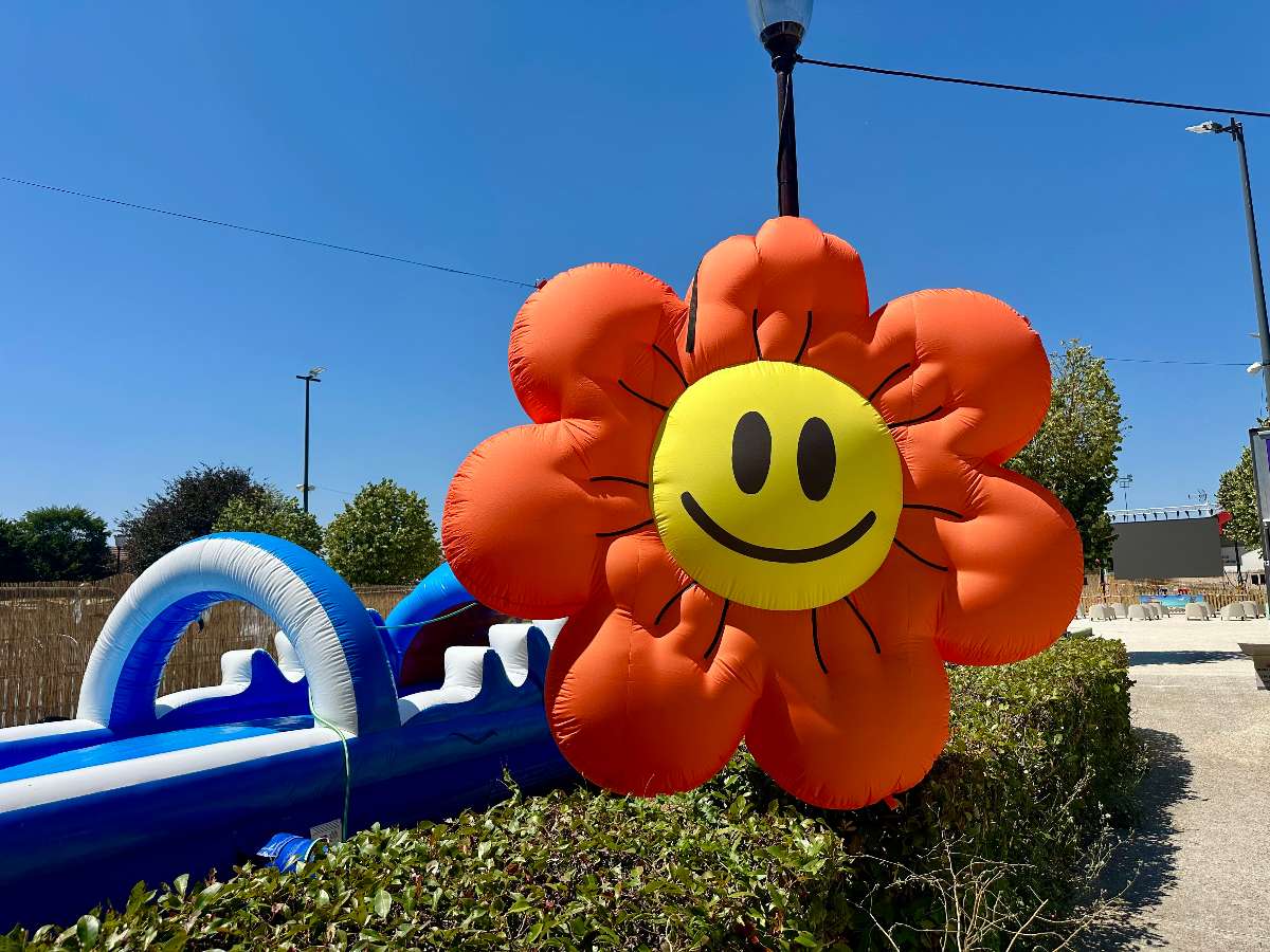 décoration gonflable en forme de fleur orange avec un visage au centre décors un festival