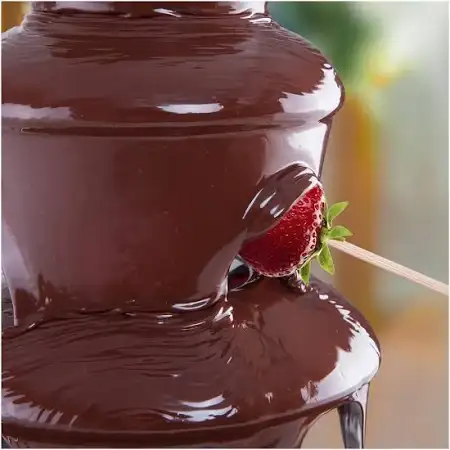 une fraise enrobé de chocolat fondu qui coule de la fontaine à chocolat