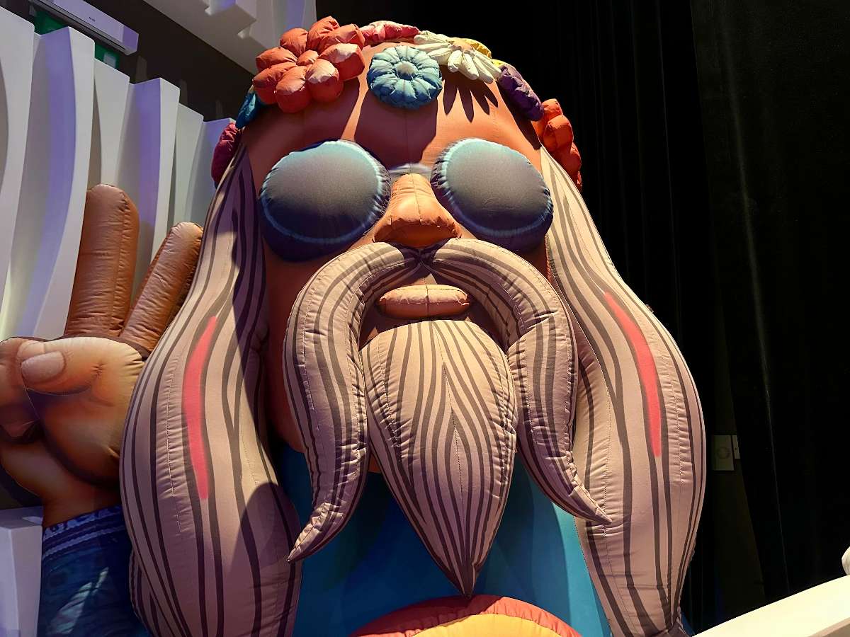 la tête du hippie gonflable de près avec ses lunettes de soleil noir et sa barbe et longue moustache 