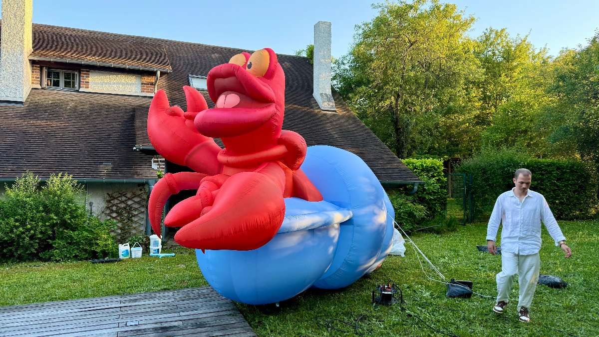 décoration Homard rouge et bleu clair de 3 mètres de haut gonflable sur le thème de la plage vue de biais avec une personne à coté