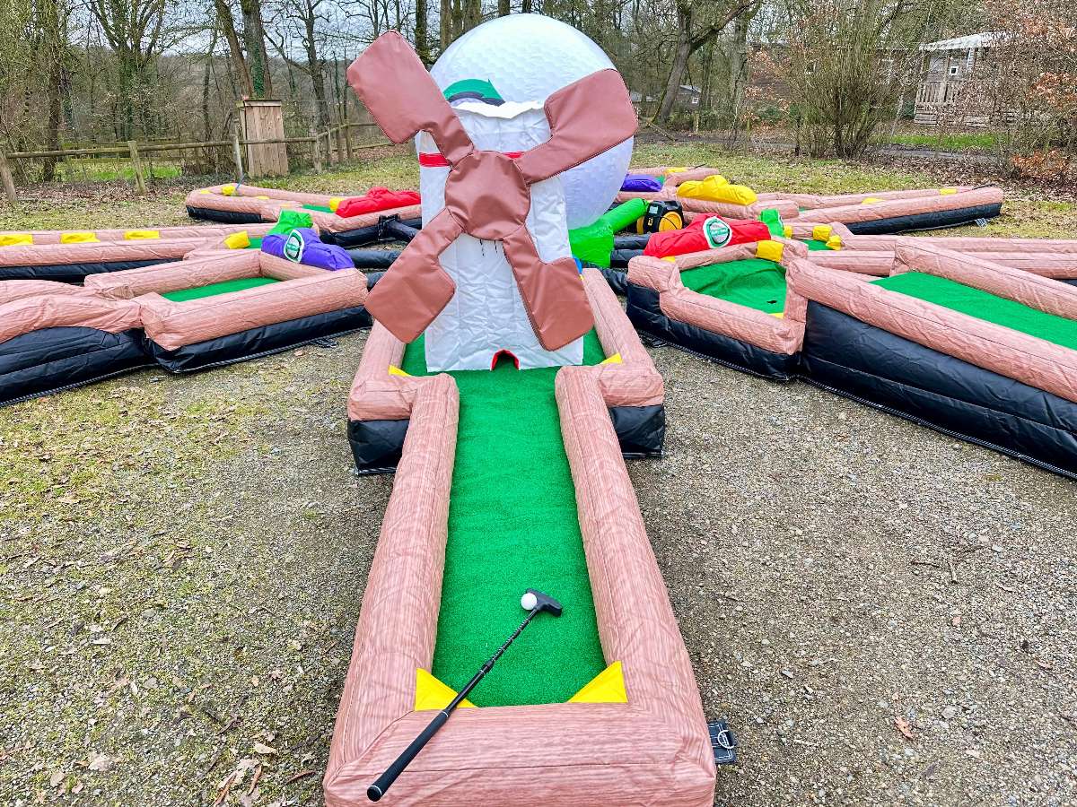 piste de mini golf avec un club en plastique bleu avec des obstacles jaune et un moulin géant