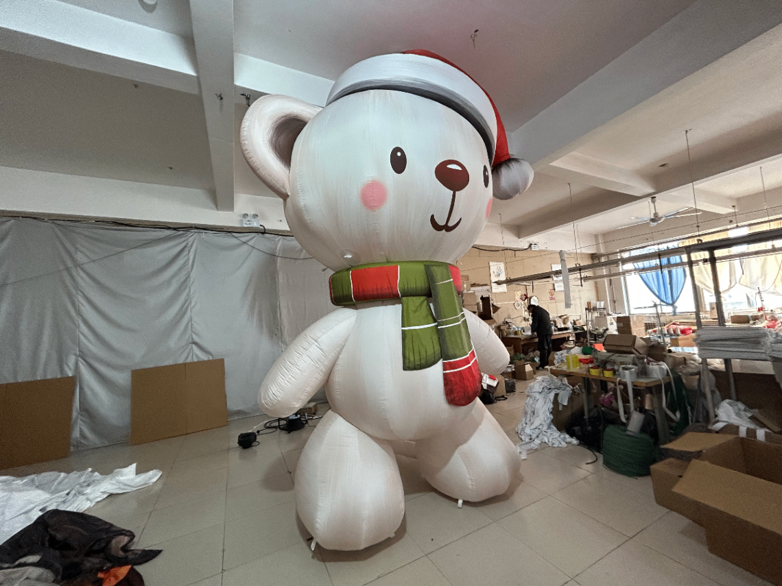 Nounours géant gonflable blanc avec un bonnet de noël rouge et une écharpe rouge et verte