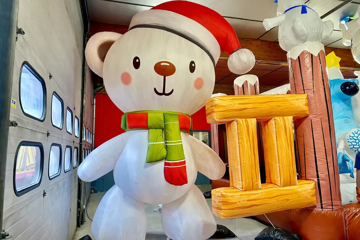 Nounours géant gonflable avec un bonnet de noël rouge et une écharpe rouge et verte