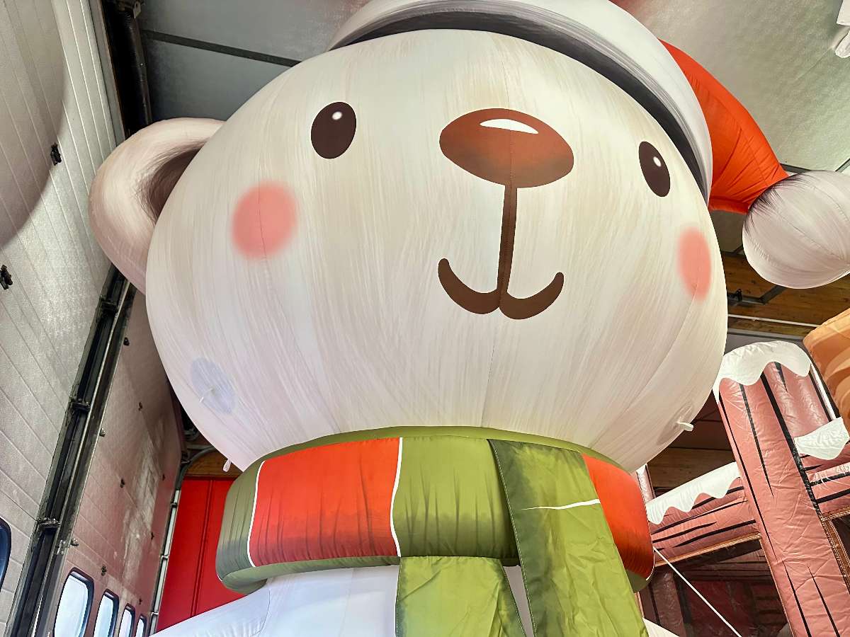 tête de la décoration du nounours géant gonflable de noël vue de face avec son écharpe rouge et verte