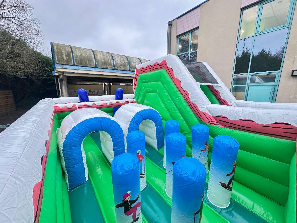 vue sur l'ensemble des obstacles du parcours gonflable de couleur bleu blanc et vert 