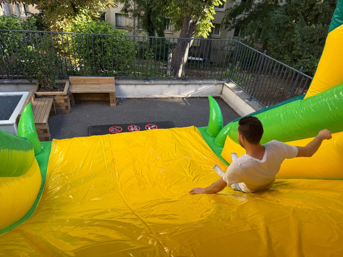 un homme  glisse du toboggan jaune et vert du parcours d'obstacles roi lion 