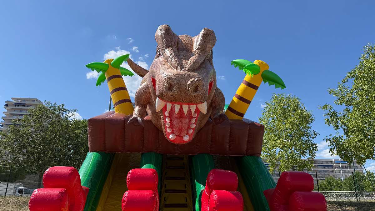 dinosaure au dessus du toboggan avec deux palmier un de chaque cote du dinosaure